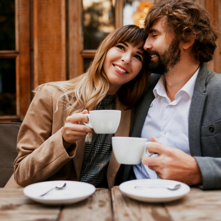 The man and the woman drink coffe and smile